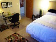 bed white linens multi coloured rug desk black chair